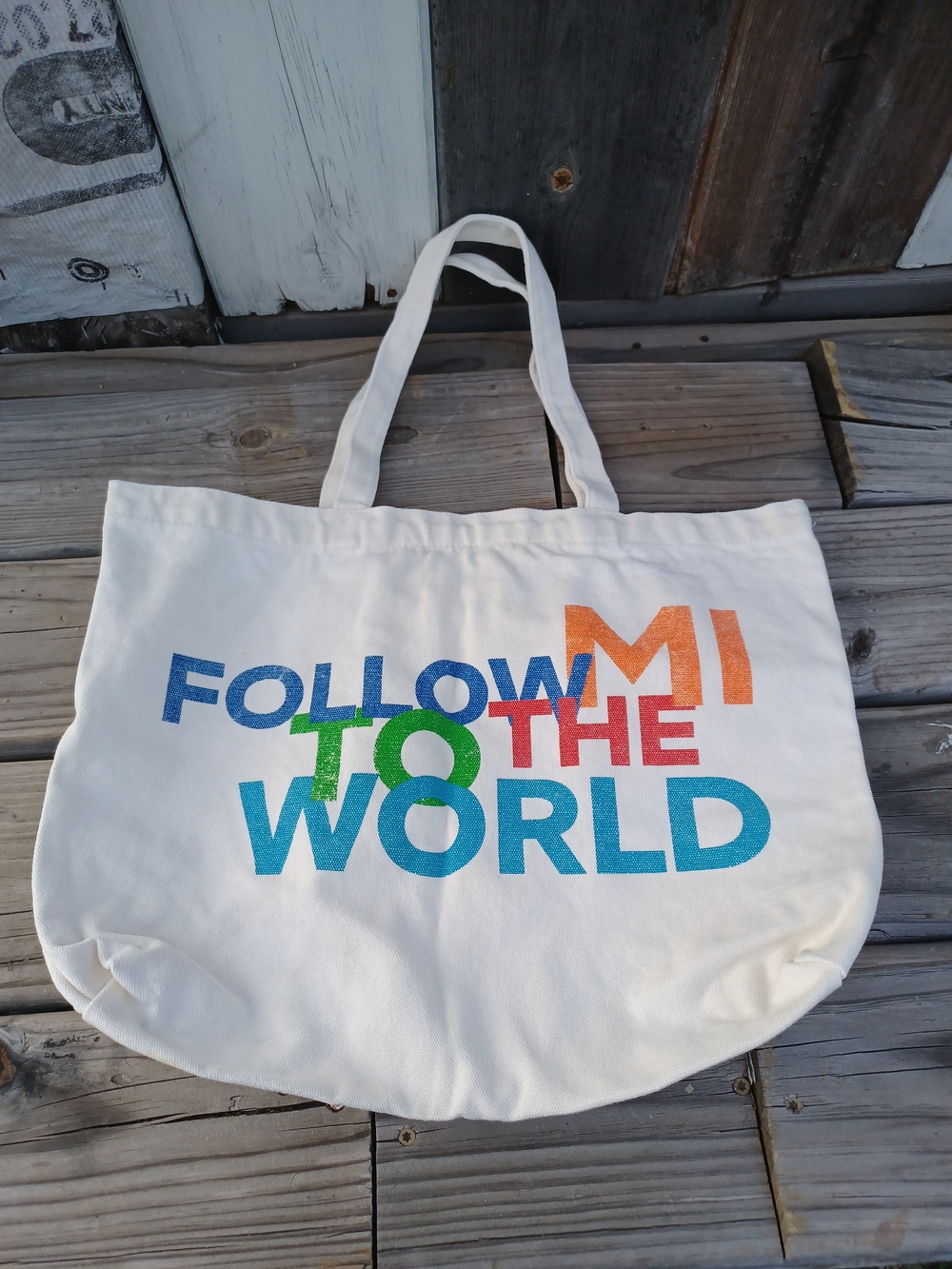 MCA Follow the World Off White Canvas Tote Bag with Multicolor Text